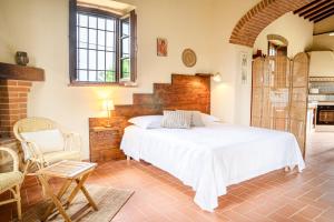 a bedroom with a large white bed and a chair at La Capanna di Montauto in San Gimignano