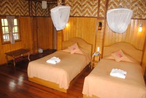 two beds in a room with wooden walls and wood floors at Golden Island Cottages Thale U Hotel in Ywama