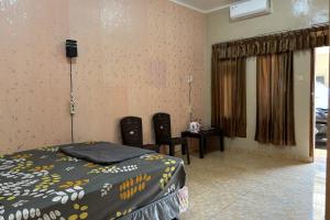 a bedroom with a bed and a table and two chairs at Family 24 Hotel near Pantai Cipatujah in Cipatujah +9 photos