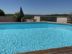 une grande piscine bleue avec une table et un parasol dans l'établissement Coquelicot, à Montagnac 16 autres photos