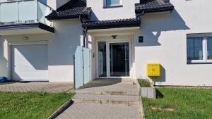 una casa blanca con una puerta y un buzón amarillo en Kropla w morzu 12, en Darłowo