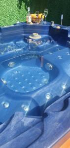 a blue tub with a table and glasses of wine at Къща за гости Ози in Ovchartsi