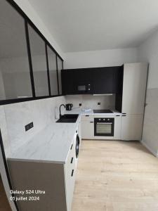 a white kitchen with a sink and a stove at Joli studio en centre-ville in Corte