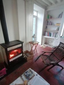 a living room with a fireplace and a chair at Natur und Sterne in Arleuf
