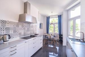 Una cocina blanca con gabinetes blancos y una mesa. en TOTU HOME Wajdeloty 5 Rooms Gdańsk, en Gdansk