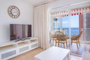 a living room with a television and a table with chairs at Serisol Holidays in Benidorm