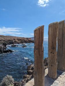 a group of wooden posts on the edge of a body of water at Sunny Seas Hideaway Apartment in Los Abrigos