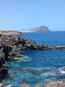 an island in the ocean with blue water and rocks at Sunny Seas Hideaway Apartment in Los Abrigos