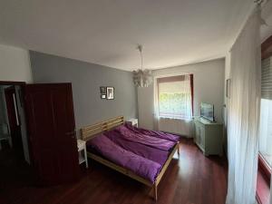 a bedroom with a purple bed and a window at Luxury Apartman in Baja