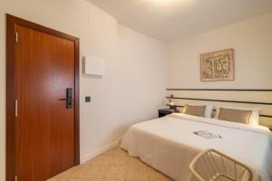 a bedroom with a bed and a wooden door at Hotel Robson - Smart Hotel in Lloret de Mar