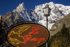a sign on a pole in front of a mountain at Hotel La Grange - Animal Chic Hotel in Courmayeur