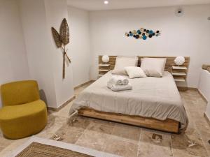 阿维尼翁Les Carmes - Le charme de la pierre en Intras Muros的一间卧室,有一张床和一把黄色椅子