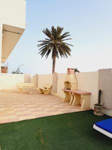 a patio with benches and a palm tree in the background at Villa HANA in Midoun