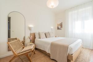 a white bedroom with a large bed and a chair at Casa Vela by Rent All Como in Sala Comacina