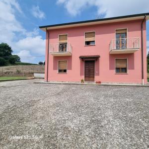 a pink house on a gravel road at B&b da Tommy Casa Vacanze in Alseno