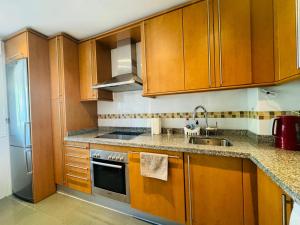 eine Küche mit Holzschränken und einer Spüle in der Unterkunft Vista Calanova Golf Club Apartment, 2BD Seaviews in La Cala de Mijas