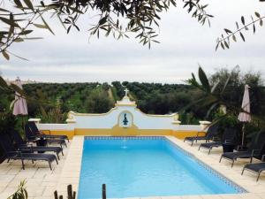 a swimming pool with chairs and a building at Monte dos Aroeirais in Fronteira