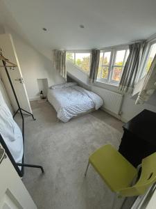 a bedroom with a bed and a chair and windows at Cosy attic flat with views in London