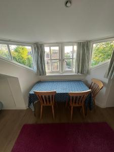 a dining room with a table and chairs and windows at Cosy attic flat with views in London +16 photos