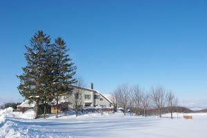 Una casa con un árbol de Navidad en la nieve en Akane-yado, en Nakafurano