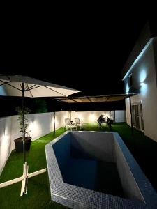 a swimming pool with an umbrella in a yard at night at Počitelj Holiday House in Počitelj