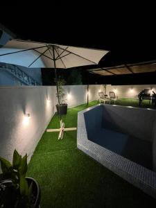 a swimming pool with an umbrella and green grass at Počitelj Holiday House in Počitelj +21 photos
