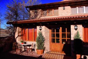 a house with a wooden door and a table and chairs at Hotel Rural La Cabaña in Palazuelos