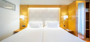 a bedroom with a large white bed with two pillows at Abba Rambla Hotel in Barcelona