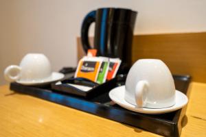 two cups sitting on a table with a coffee pot at Abba Rambla Hotel in Barcelona