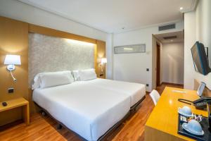 a bedroom with a large white bed and a desk at Abba Rambla Hotel in Barcelona