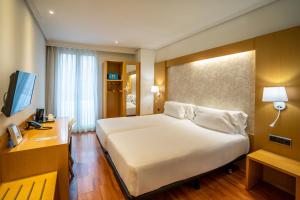 a hotel room with a large white bed and a desk at Abba Rambla Hotel in Barcelona