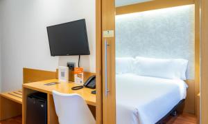 a bedroom with a bed and a desk with a television at Abba Rambla Hotel in Barcelona