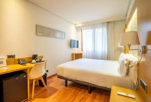 a hotel room with a bed and a desk with a computer at Abba Rambla Hotel in Barcelona