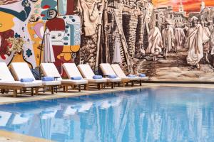 a pool with chaise lounge chairs in front of a mural at Blue Sea Le Printemps in Marrakech