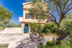 a house with a stone wall and a blue door at Apartments Kukljica Ugljan in Kukljica