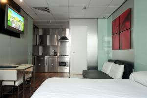 a bedroom with a white bed and a kitchen at Stylotel in London