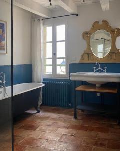 a bathroom with a tub and a sink and a mirror at Le Coucou Montcuq in Montcuq