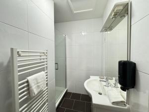 une salle de bain blanche avec lavabo et douche dans l'établissement Maison Évasion Vichy14 couchages, à Vichy 18 autres photos