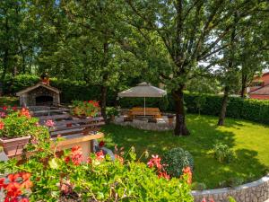 a garden with a bench and an umbrella and some flowers at Apartment Marijo by Interhome in Matulji