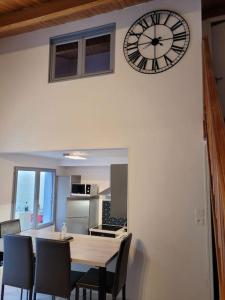 a clock on a wall above a table and chairs at Maison entière en centre ville in Saint-Maur-des-Fossés