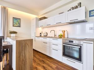 a kitchen with white cabinets and a wooden floor at Apartment Horní Mísečky-2 by Interhome in Vítkovice