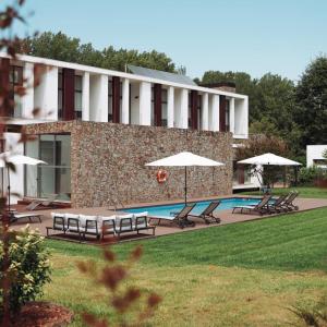 科尔武河畔米兰达Hotel Parque Serra da Lousã的一个带游泳池、椅子和遮阳伞的度假村