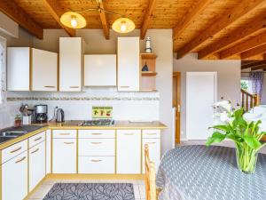 a kitchen with white cabinets and a table with a vase of flowers at Holiday Home Stereden Vor by Interhome in Primelin