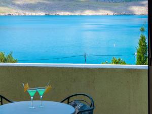 a table with two drinks on a balcony with a view of the water at Apartment Vlasta-1 by Interhome in Jadranovo