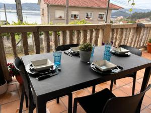 einen schwarzen Tisch mit Tellern und Gläsern auf dem Balkon in der Unterkunft Casita rural acogedora in Combarro