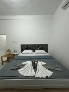 a bed with white robes on top of it at Black Sweet Homestay Dua in Gili Air