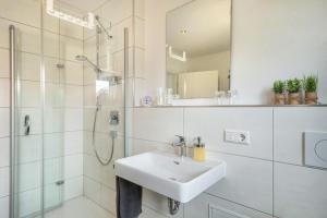 a white bathroom with a sink and a shower at Time Out - Appartement Bodensee in Friedrichshafen +15 photos