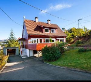 una casa con una entrada para autos en frente de ella en Kjellerleilighet i Fana til leie-med gratis parkering og mange kollektiv reisemuligheter, en Bergen