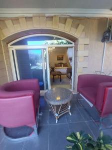 a patio with two red chairs and a table at ڤيلا فاخرة لك بجميع الخدمات بالساحل الشمالي in Abû Zeira