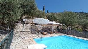 a swimming pool with an umbrella and two chairs at IthakiHouse II in Vathi